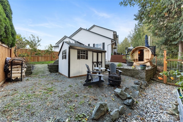 back of property with an outdoor structure and an outdoor fire pit