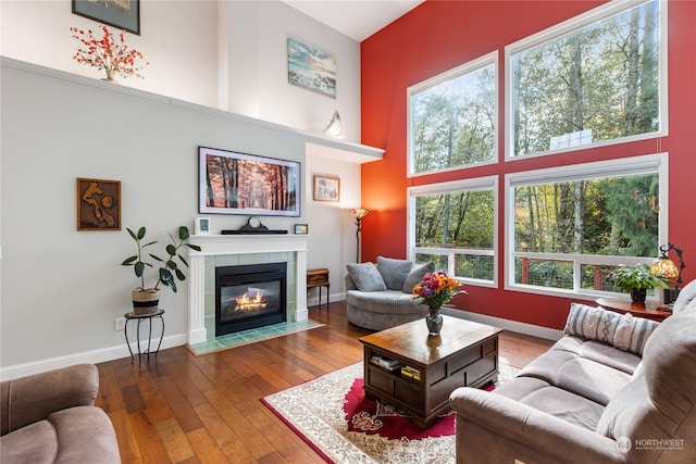 living room with hardwood / wood-style flooring, a towering ceiling, and a fireplace