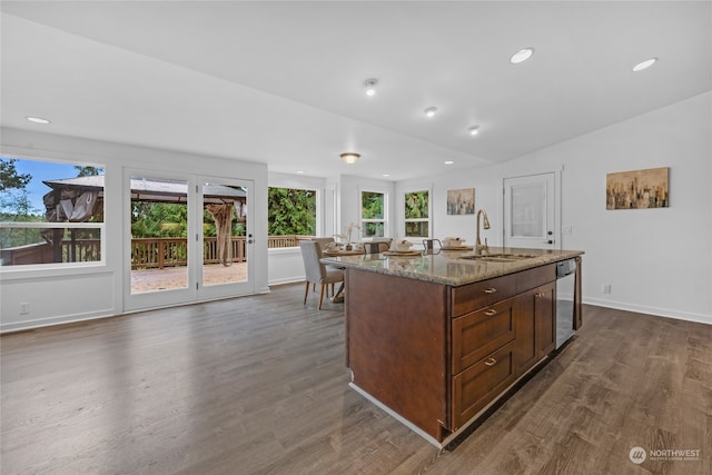 kitchen featuring dishwasher, sink, dark hardwood / wood-style flooring, vaulted ceiling, and a kitchen island with sink