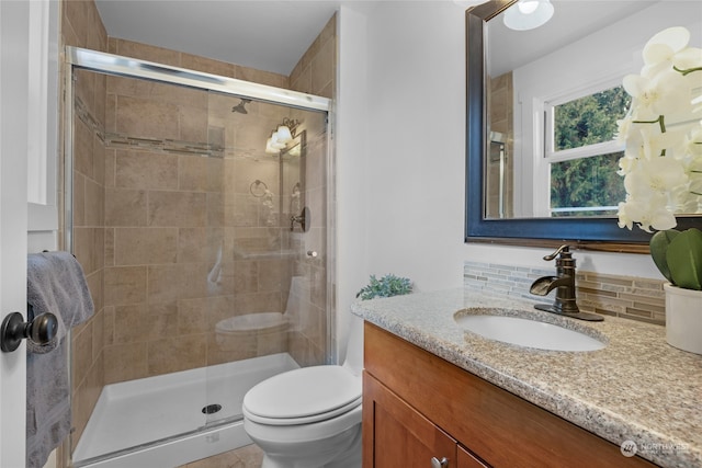 bathroom featuring tasteful backsplash, a shower with shower door, toilet, vanity, and tile patterned flooring