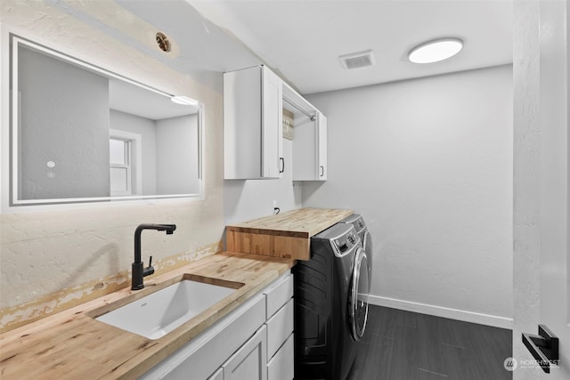 clothes washing area with cabinets, sink, and separate washer and dryer