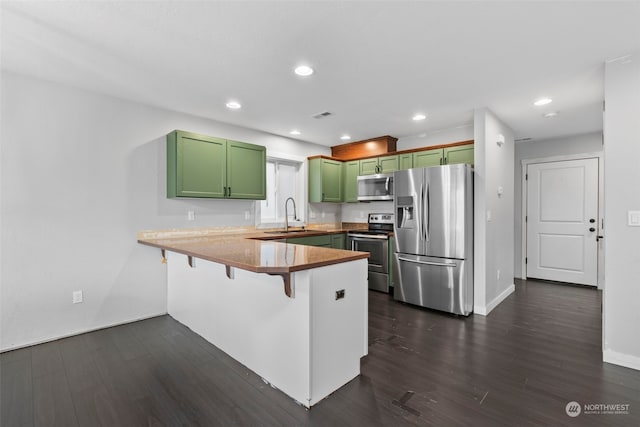 kitchen with appliances with stainless steel finishes, dark hardwood / wood-style flooring, kitchen peninsula, and a kitchen breakfast bar