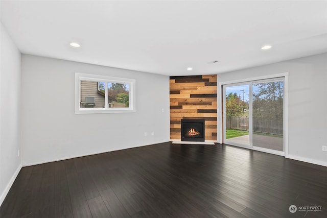 unfurnished living room with hardwood / wood-style floors, a healthy amount of sunlight, and a large fireplace