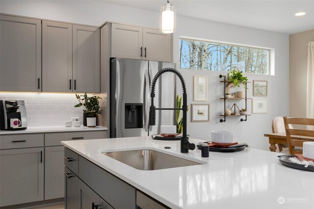 kitchen featuring pendant lighting, gray cabinetry, sink, and tasteful backsplash