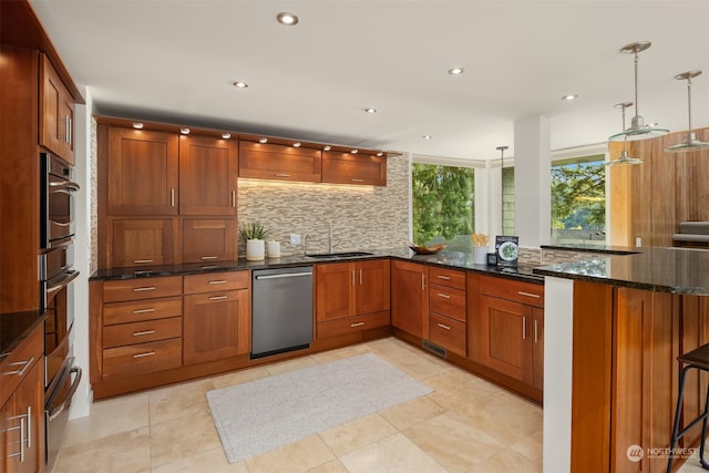 kitchen featuring dark stone counters, sink, hanging light fixtures, appliances with stainless steel finishes, and kitchen peninsula