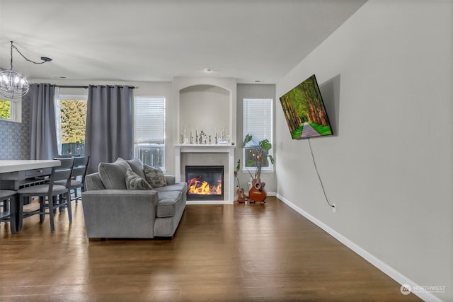 living room featuring a notable chandelier, a tile fireplace, and dark hardwood / wood-style flooring