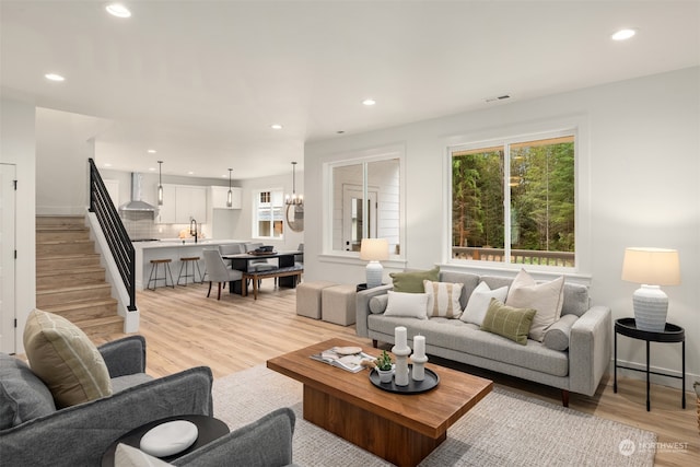 living room with light hardwood / wood-style flooring, a notable chandelier, and sink