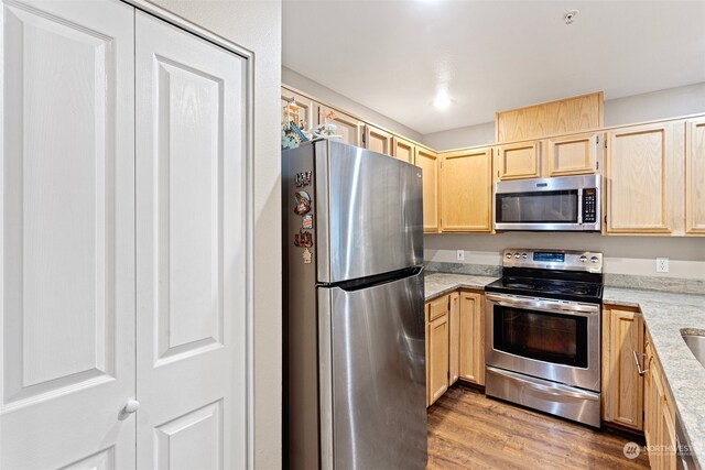 kitchen featuring light brown cabinets, appliances with stainless steel finishes, and hardwood / wood-style floors