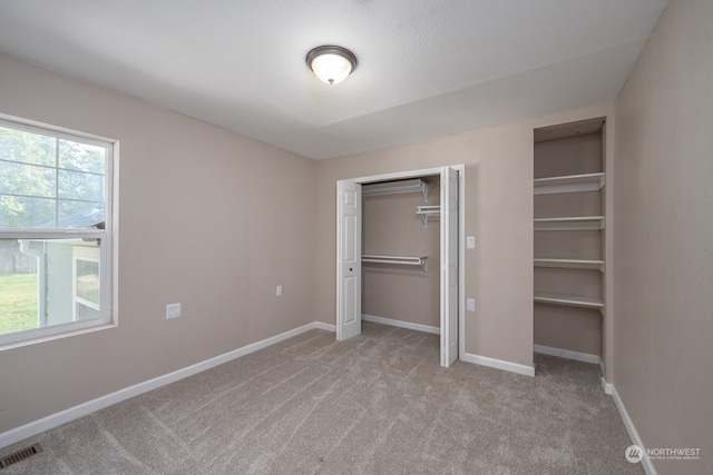 unfurnished bedroom with a closet and light colored carpet