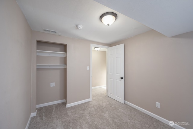 unfurnished bedroom featuring light carpet and a closet