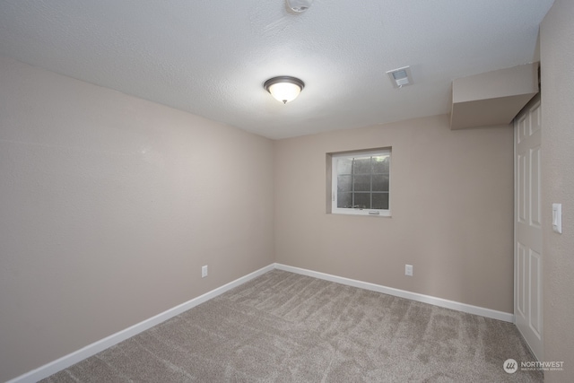 spare room with a textured ceiling and light colored carpet