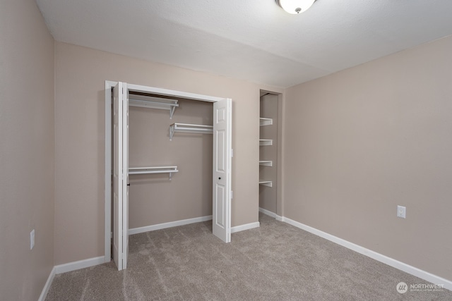 unfurnished bedroom with a closet, a textured ceiling, and light colored carpet