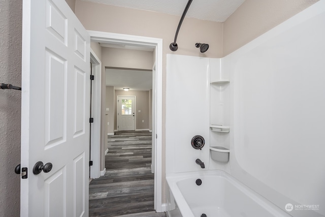 bathroom featuring a textured ceiling, hardwood / wood-style flooring, and  shower combination