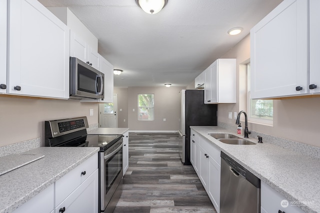 kitchen with appliances with stainless steel finishes, sink, dark hardwood / wood-style floors, and white cabinets