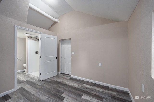 unfurnished bedroom featuring dark wood-type flooring, connected bathroom, and high vaulted ceiling