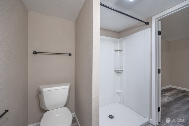 bathroom featuring toilet, a shower, a textured ceiling, and hardwood / wood-style floors