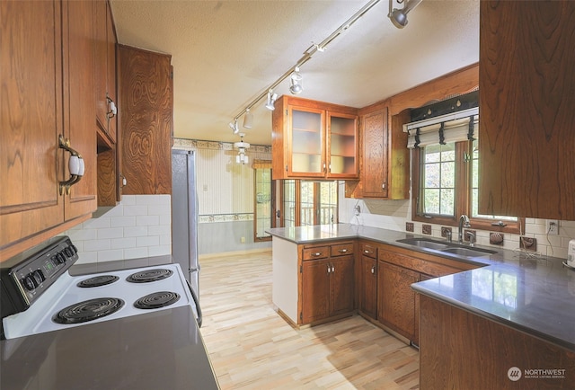 kitchen with range with electric stovetop, sink, stainless steel fridge, light hardwood / wood-style floors, and kitchen peninsula