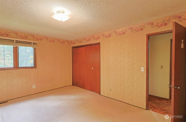 unfurnished bedroom featuring carpet floors, a closet, and a textured ceiling