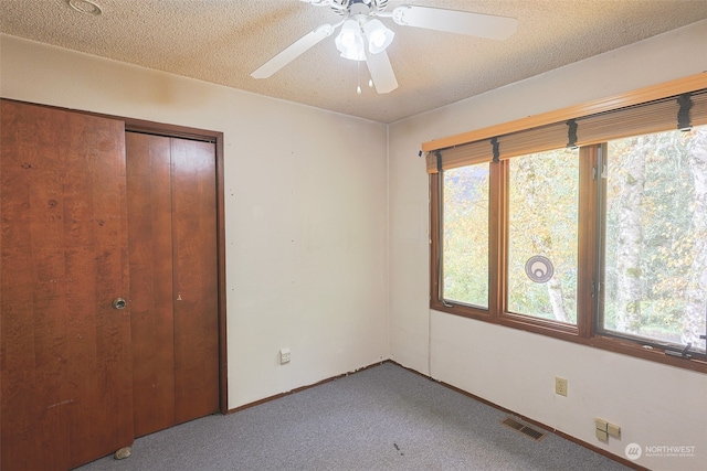 unfurnished bedroom featuring ceiling fan, carpet, a textured ceiling, and a closet