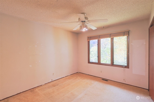 unfurnished room featuring ceiling fan, light carpet, and a textured ceiling