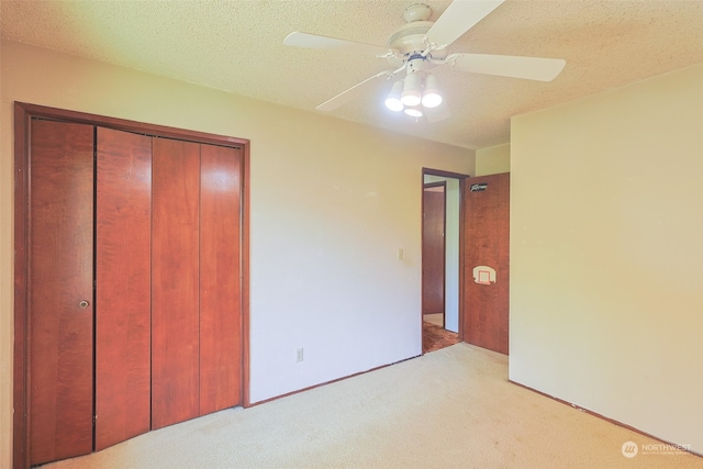 unfurnished bedroom featuring light carpet, ceiling fan, a closet, and a textured ceiling