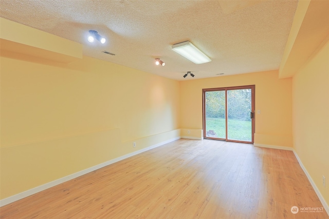 empty room featuring a textured ceiling and light wood-type flooring