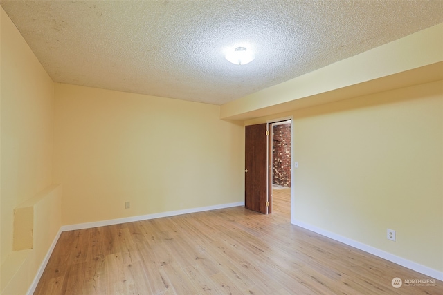 unfurnished room featuring a textured ceiling and light hardwood / wood-style flooring