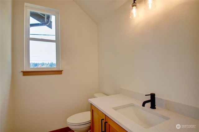 bathroom featuring vanity, toilet, and vaulted ceiling