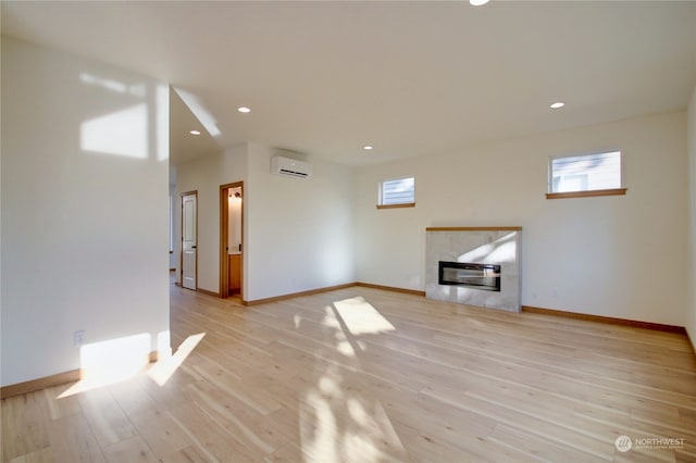 unfurnished living room with a wall unit AC, light hardwood / wood-style floors, and a fireplace