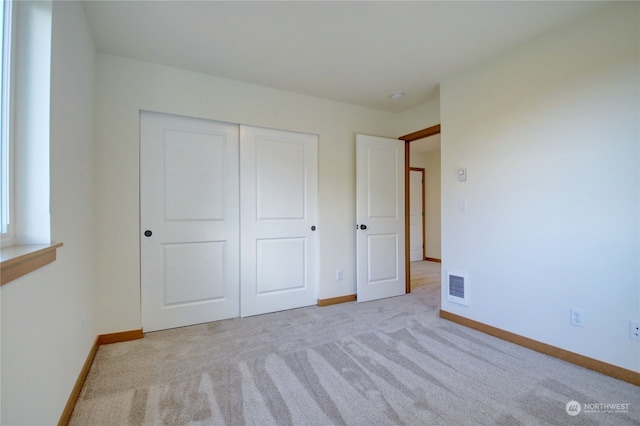 unfurnished bedroom featuring light carpet and a closet