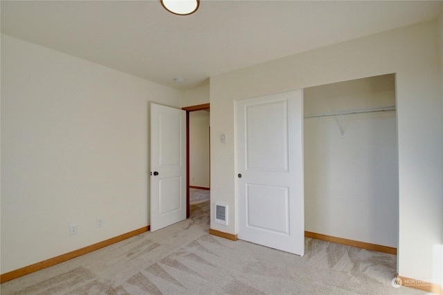 unfurnished bedroom featuring light carpet and a closet