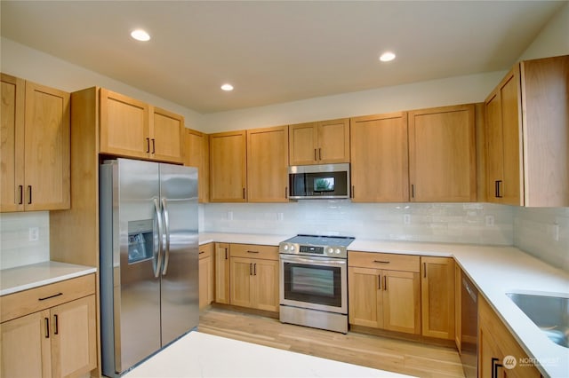 kitchen featuring light hardwood / wood-style floors, sink, appliances with stainless steel finishes, light brown cabinets, and backsplash