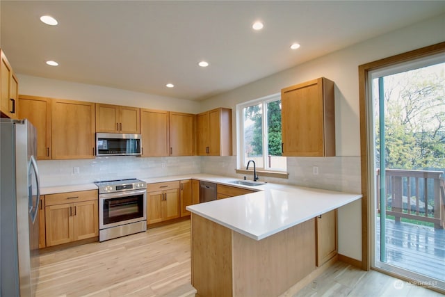 kitchen with stainless steel appliances, light hardwood / wood-style floors, sink, and kitchen peninsula