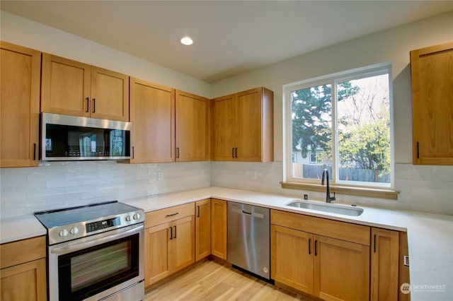 kitchen featuring light wood-type flooring, stainless steel appliances, sink, and backsplash