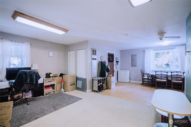 home office with ceiling fan, electric panel, washer / clothes dryer, and light hardwood / wood-style flooring