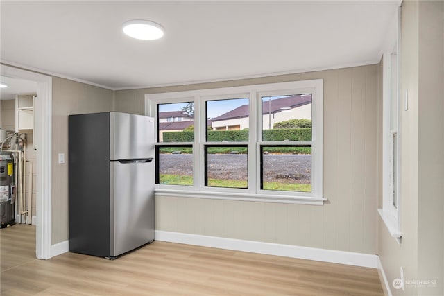 kitchen with stainless steel fridge, light hardwood / wood-style flooring, electric water heater, and wood walls