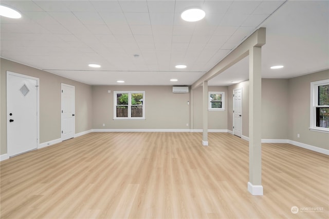 basement featuring light hardwood / wood-style flooring and a wall mounted air conditioner