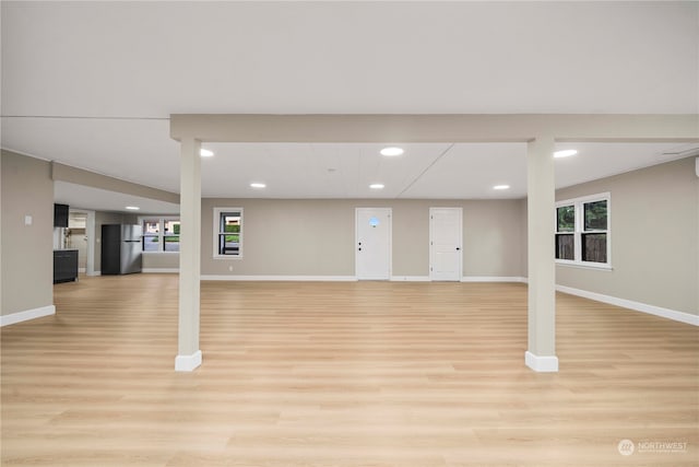 basement featuring light hardwood / wood-style flooring and stainless steel refrigerator