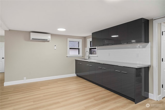 kitchen featuring sink, backsplash, light hardwood / wood-style flooring, and a wall mounted air conditioner