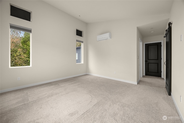 carpeted empty room with a barn door and a wall unit AC