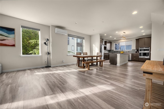 living room with a wall mounted air conditioner and light wood-type flooring