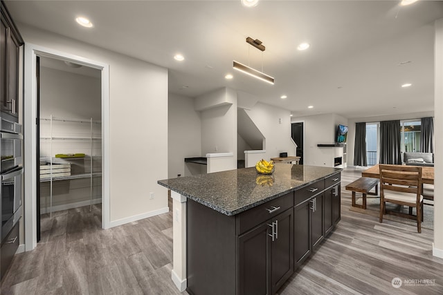 kitchen featuring dark brown cabinets, light wood-type flooring, and dark stone countertops