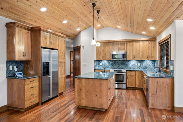 kitchen with hanging light fixtures, stainless steel appliances, a center island with sink, vaulted ceiling, and dark hardwood / wood-style flooring