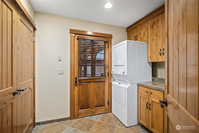 clothes washing area with cabinets and stacked washer / drying machine