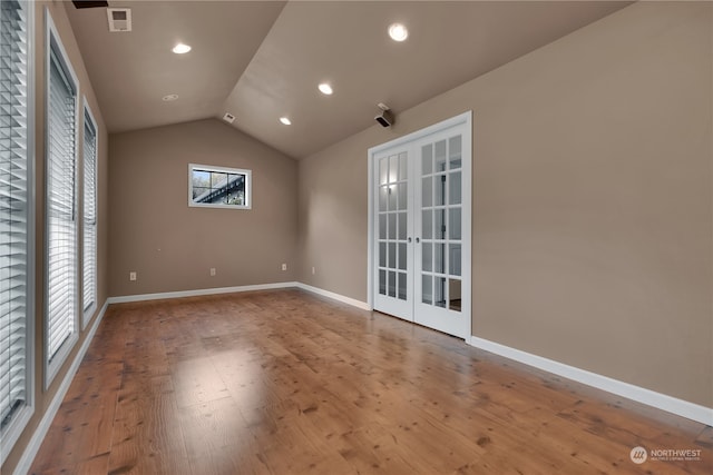 empty room featuring lofted ceiling, hardwood / wood-style floors, and french doors