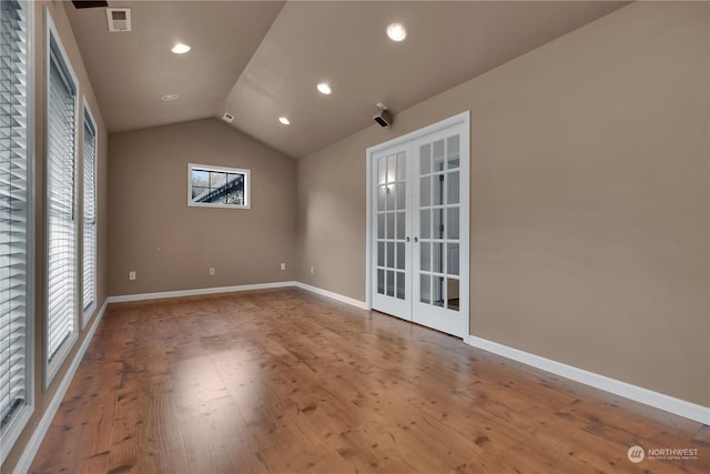 spare room with french doors, visible vents, wood finished floors, baseboards, and lofted ceiling