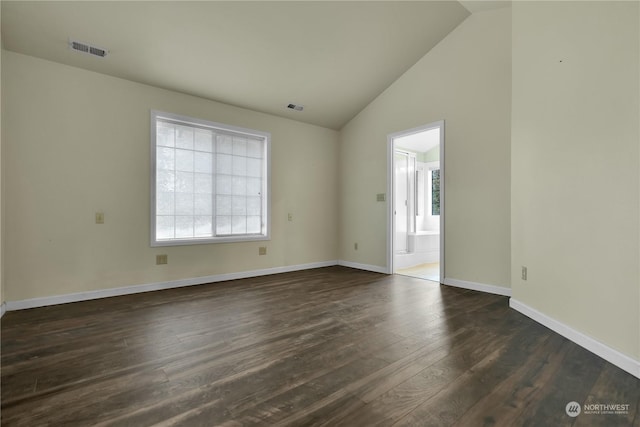empty room with visible vents, baseboards, dark wood-type flooring, and lofted ceiling