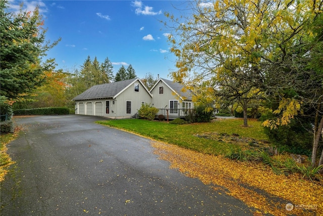view of side of home with a wooden deck, driveway, board and batten siding, an attached garage, and a yard