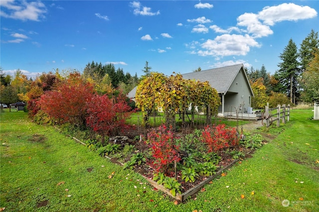 view of property exterior featuring fence, a yard, and a garden