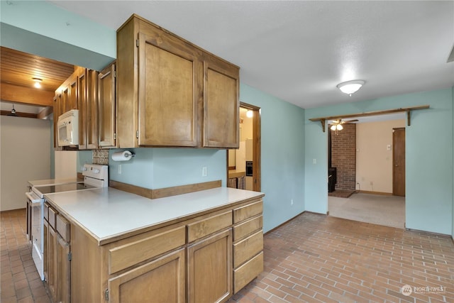 kitchen featuring a ceiling fan, brick floor, white appliances, and light countertops